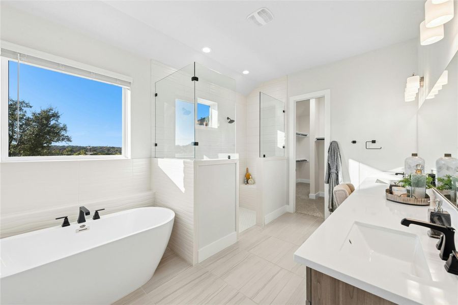Full bathroom featuring a spacious closet, a freestanding bath, a walk in shower, double vanity, and recessed lighting Full bathroom featuring a spacious closet, a freestanding bath, a walk in shower, double vanity, and recessed lighting