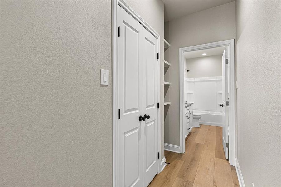 Hallway featuring light wood-style floors and a textured wall Hallway featuring light wood-style floors and a textured wall