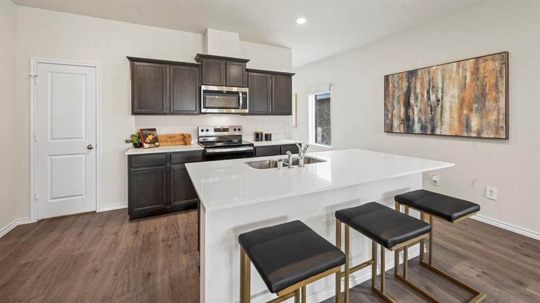 Kitchen with stainless steel appliances, a breakfast bar, dark wood-type flooring, dark wood finish cabinets, and recessed lighting