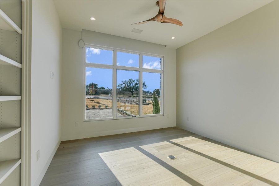Empty room with ceiling fan, light wood finished floors, and recessed lighting