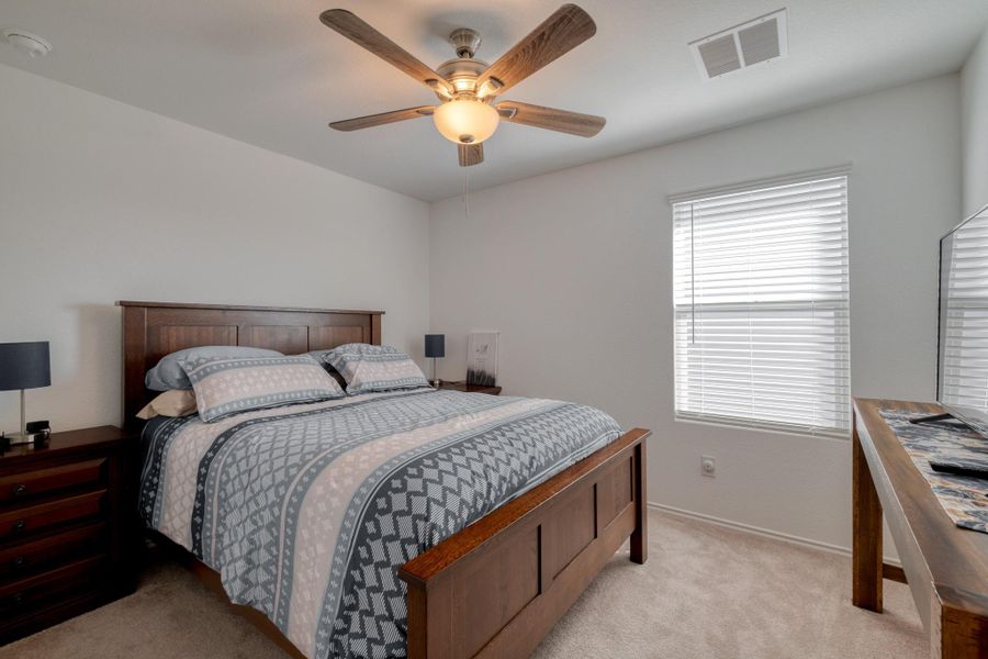 This inviting room features a ceiling fan with integrated lighting, a window with blinds, and neutral-toned carpeting