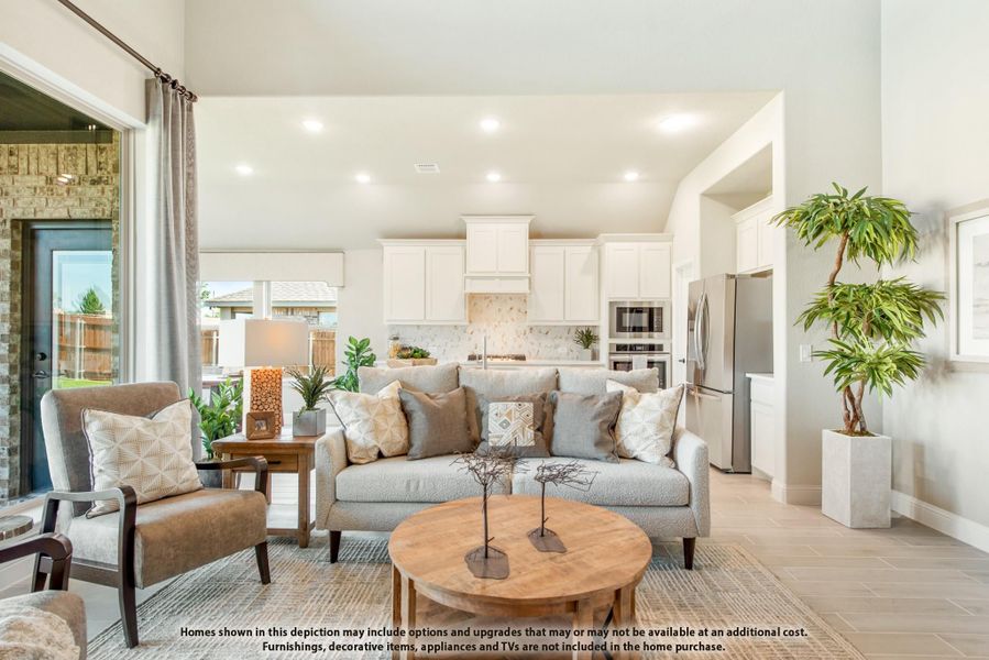 Open-concept living room with gray sofa and round wood coffee table, open to kitchen with white cabinets and stainless appliances Open-concept living room with gray sofa and round wood coffee table, open to kitchen with white cabinets and stainless appliances