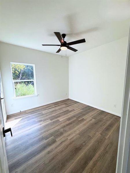 Empty room featuring dark wood-style floors and ceiling fan