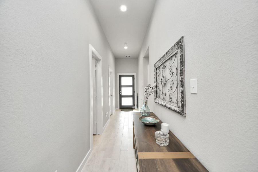 Natural daylight filters through the glass-paned front door, bouncing off the stylish flooring and setting a warm, peaceful tone right at the entrance.
