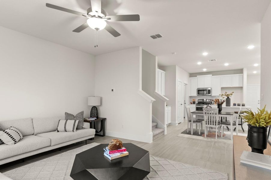 An open-concept living space with sleek flooring flows into a contemporary kitchen, perfect for modern living.
