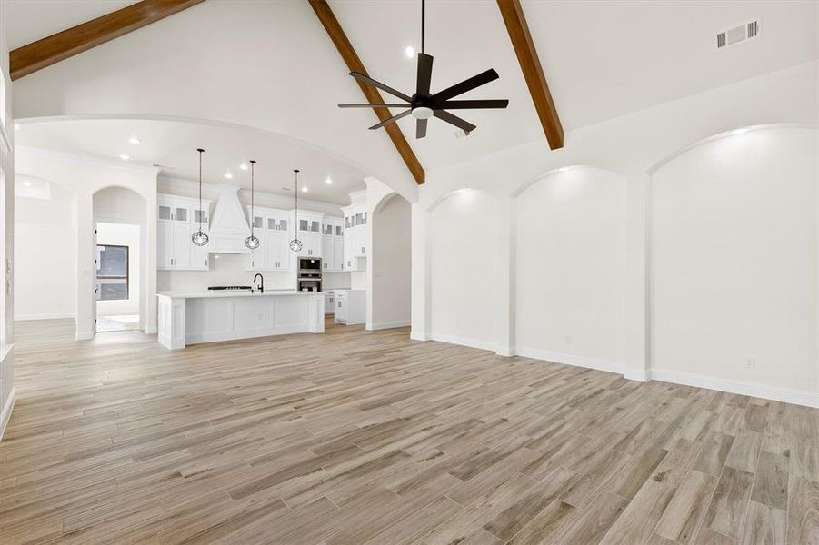 living room featuring, custom  flooring, ceiling fan, sink, beam ceiling, and high vaulted ceiling