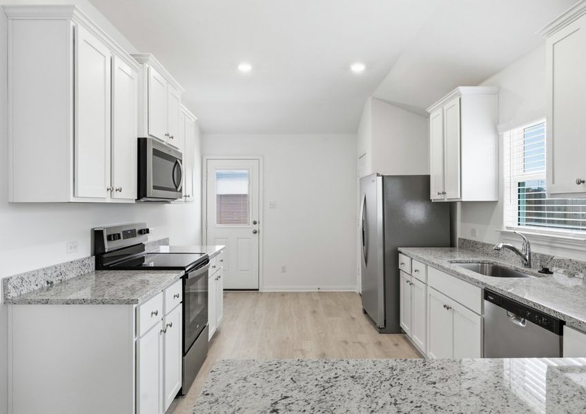 Kitchen featuring a granite island, white cabinetry, and a stainless steel range and dishwasher. Kitchen featuring a granite island, white cabinetry, and a stainless steel range and dishwasher.