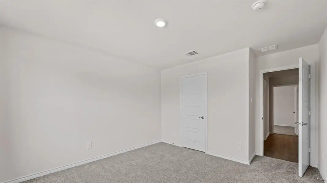 Neutral wall finishes with recessed lighting and gray carpeting Neutral wall finishes with recessed lighting and gray carpeting