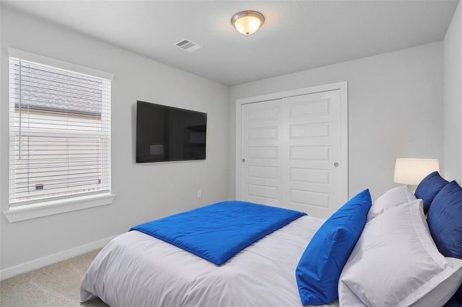 Secondary bedroom features plush carpet, custom paint and a large window.