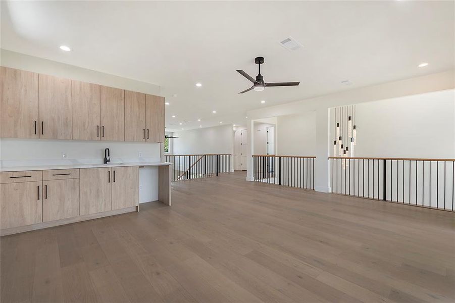 Kitchen with light brown cabinets, hardwood / wood-style floors, sink, and ceiling fan