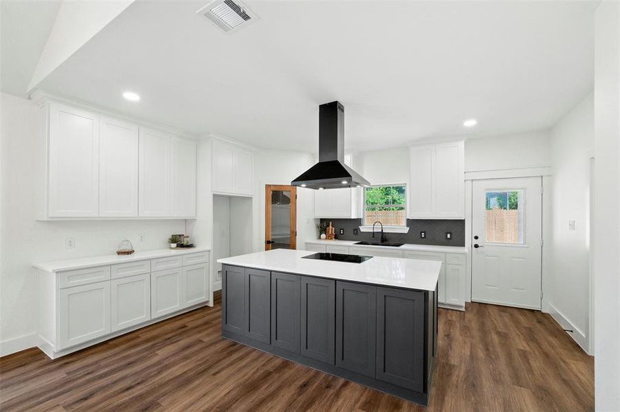 Kitchen featuring island range hood, white cabinets, dark wood-type flooring, recessed lighting, and light countertops
