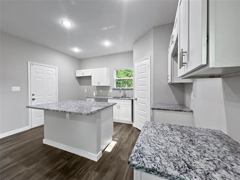 Kitchen with sink, white cabinetry, dark hardwood / wood-style flooring, and a kitchen island