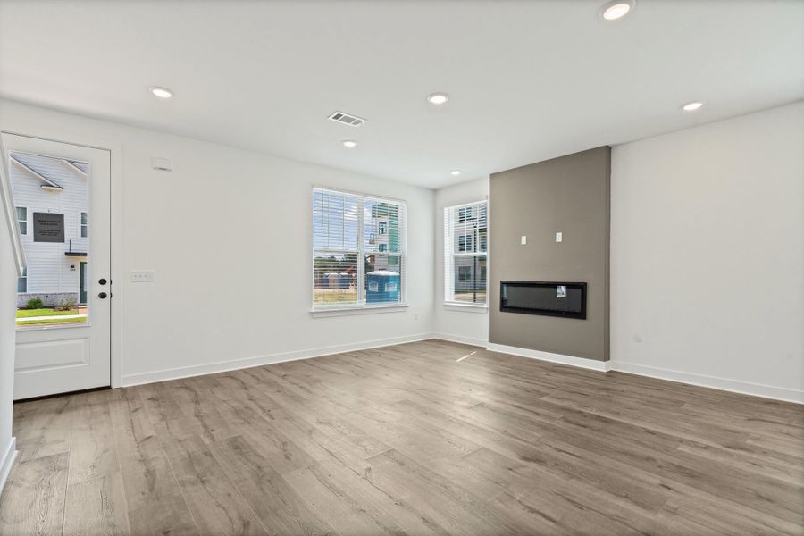 Recessed lighting, wood-finish flooring, multiple windows, built-in electric fireplace, and a feature wall
