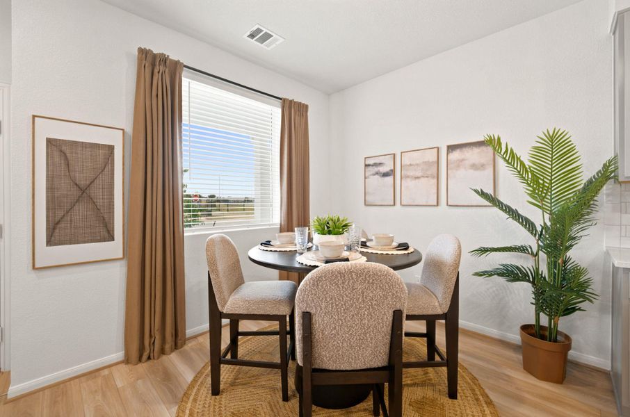A light-filled dining space offers warm wood flooring and a large window looking outdoors.