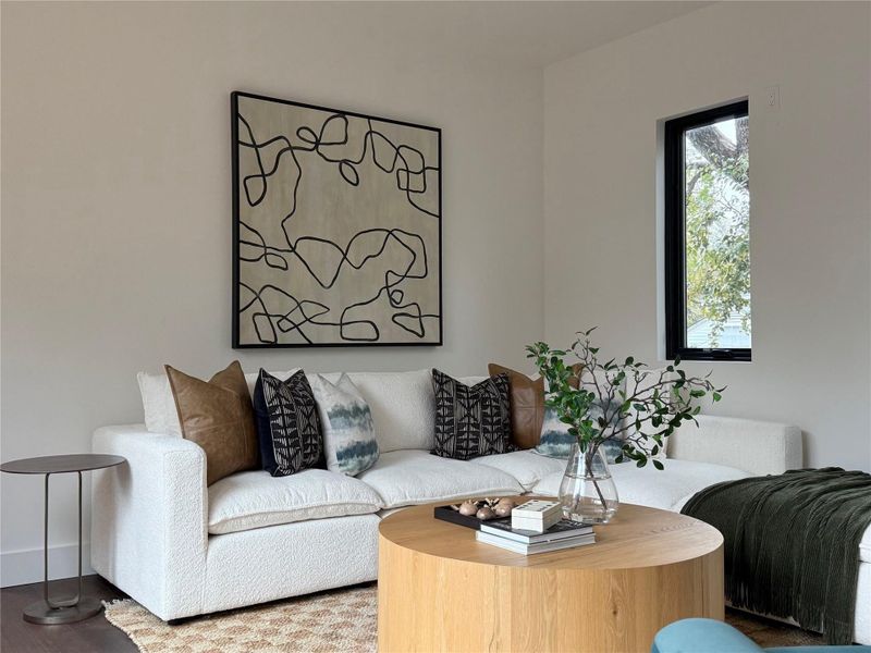 Living area featuring a light color palette, recessed lighting, and a prominent window with a black frame