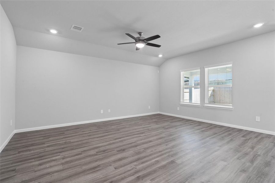 A bright and airy open-concept space featuring LVP flooring, high sloped ceilings with recessed lighting and ceiling fan, and abundant natural light from large windows (fitted with blinds). A bright and airy open-concept space featuring LVP flooring, high sloped ceilings with recessed lighting and ceiling fan, and abundant natural light from large windows (fitted with blinds).