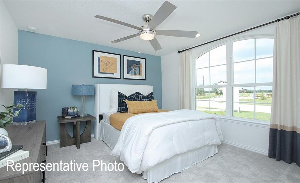 Bedroom featuring an arched window, ceiling fan with light fixture, and blue accent wall