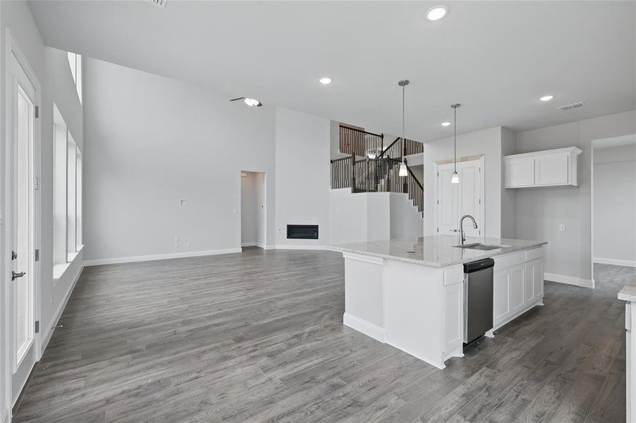 Kitchen featuring a sink, dishwasher, baseboards, white cabinetry, and wood finished floors Kitchen featuring a sink, dishwasher, baseboards, white cabinetry, and wood finished floors
