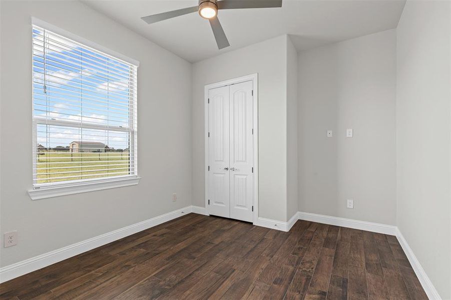 Unfurnished bedroom with dark wood-type flooring, ceiling fan, and a closet Unfurnished bedroom with dark wood-type flooring, ceiling fan, and a closet