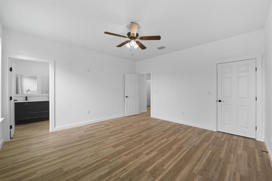 Unfurnished bedroom featuring light wood-style flooring, ensuite bath, and ceiling fan Unfurnished bedroom featuring light wood-style flooring, ensuite bath, and ceiling fan