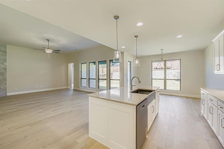 Kitchen featuring white cabinetry, recessed lighting, decorative light fixtures, light wood-style flooring, and a kitchen island with sink