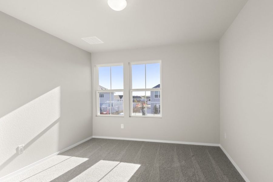 Image of a bedroom with tan carpeting, light grey walls, two windows and white trim