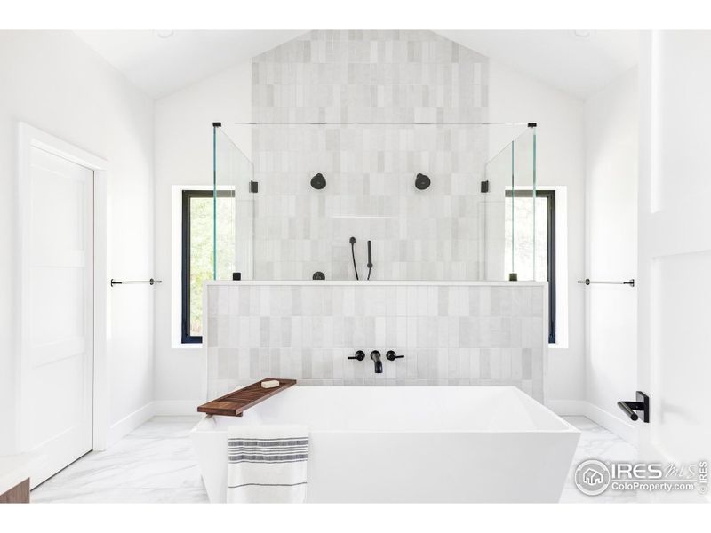 A work-of-art spa bathroom with a freestanding soaking tub, a frameless glass shower for two and two wide floating vanities.