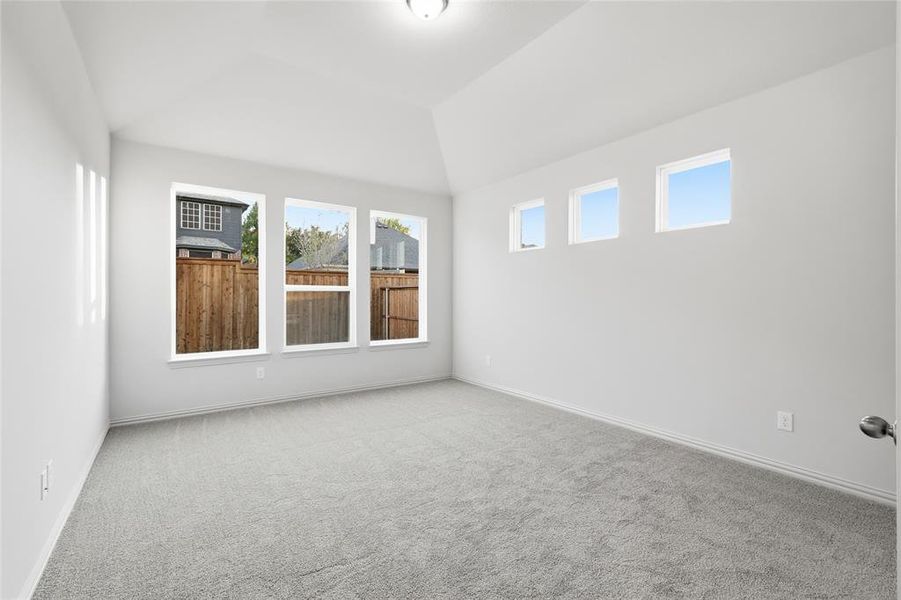 Carpeted spare room with vaulted ceiling and baseboards