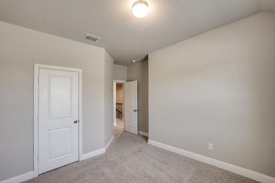 Unfurnished bedroom featuring light carpet and baseboards
