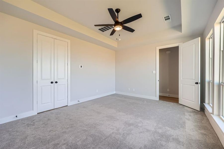 Unfurnished bedroom featuring light carpet and ceiling fan