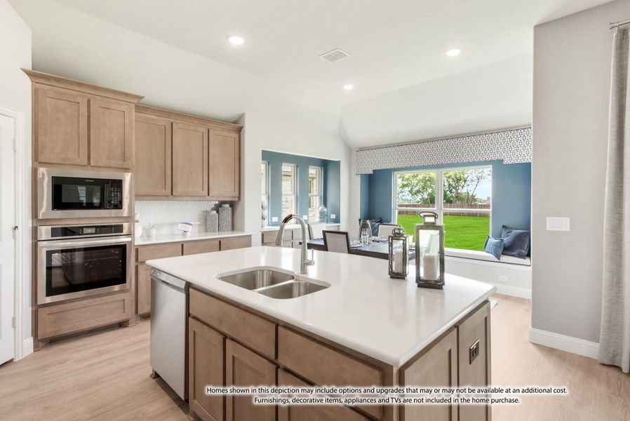 Kitchen with center island, double sink, light wood cabinets, and stainless steel appliances open to breakfast nook with window seat Kitchen with center island, double sink, light wood cabinets, and stainless steel appliances open to breakfast nook with window seat
