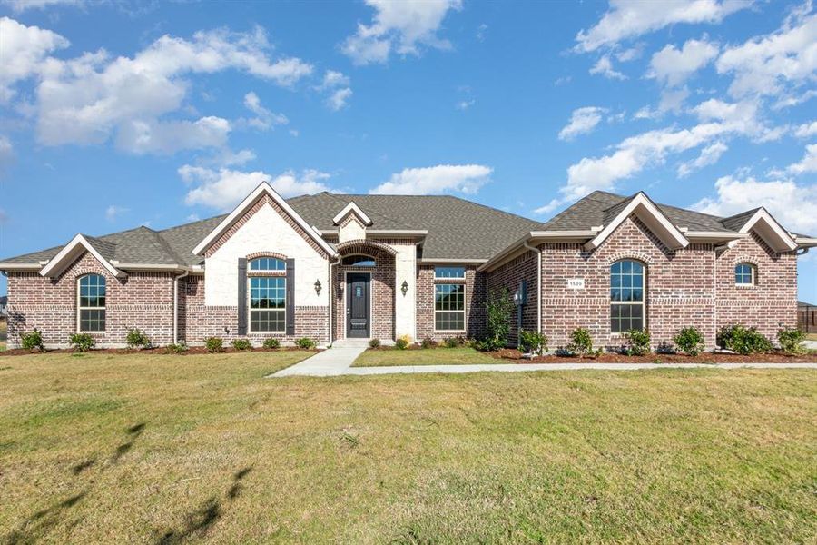 French provincial home featuring brick siding, a front lawn, and roof with shingles