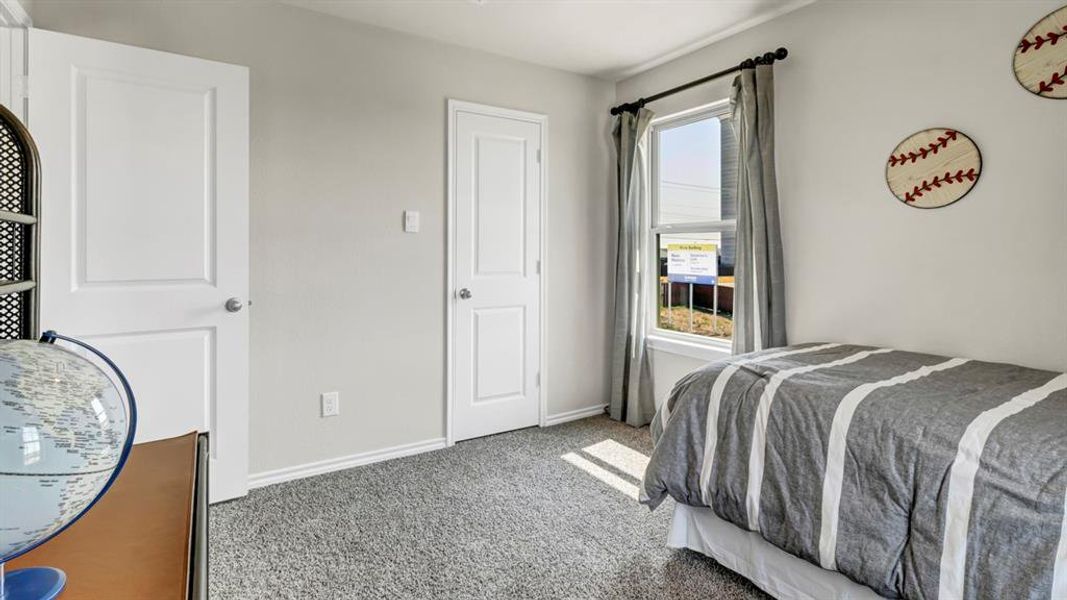 Carpeted room featuring multiple panel doors, a large window with drapes, and neutral wall paint Carpeted room featuring multiple panel doors, a large window with drapes, and neutral wall paint