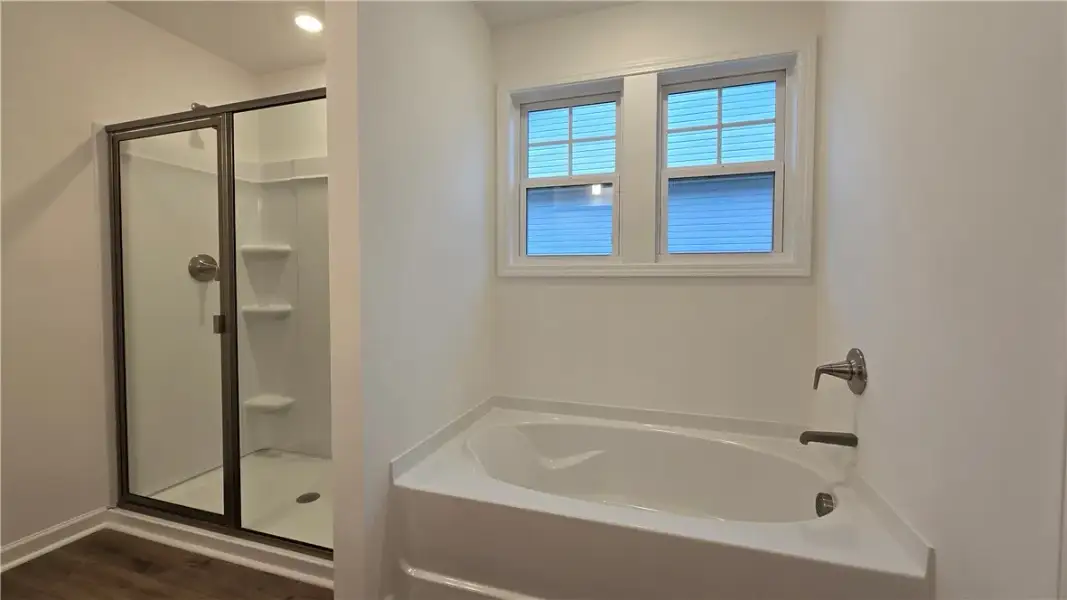 A glass-enclosed walk-in shower stands adjacent to