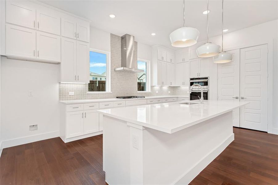 Kitchen with white cabinetry, backsplash, dark hardwood / wood-style flooring, an island with sink, and wall chimney exhaust hood