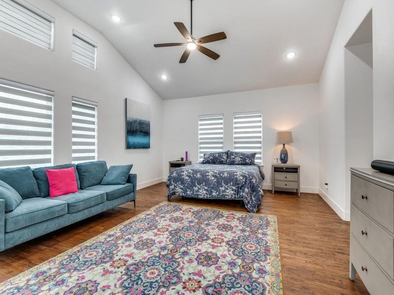 Oversized primary bedroom with a ceiling fan, wood finished floors, recessed lighting, and high vaulted ceiling