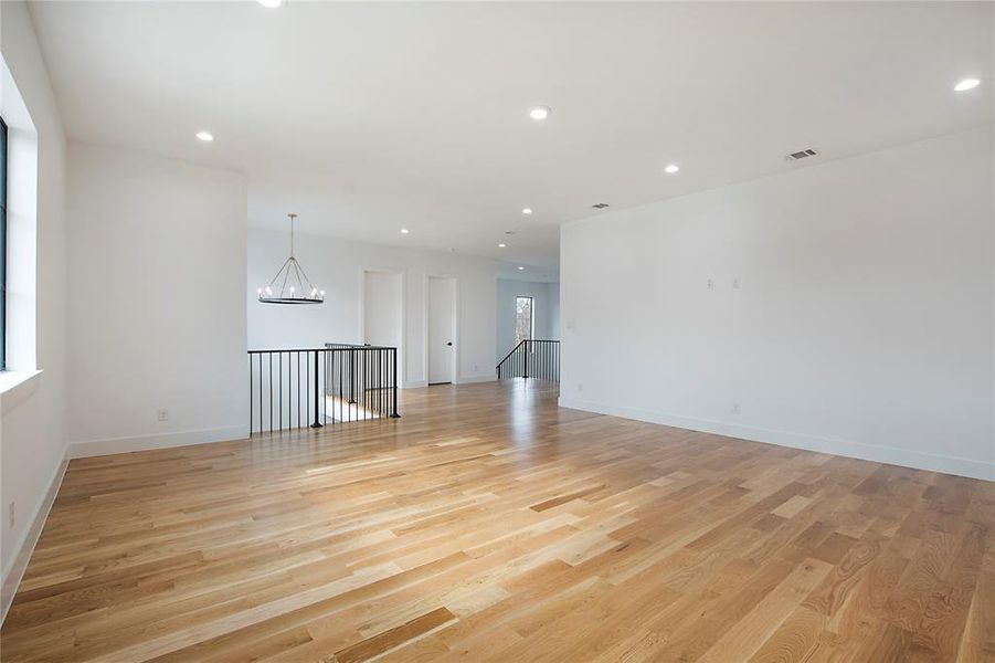 Unfurnished room with light wood-type flooring and an inviting chandelier