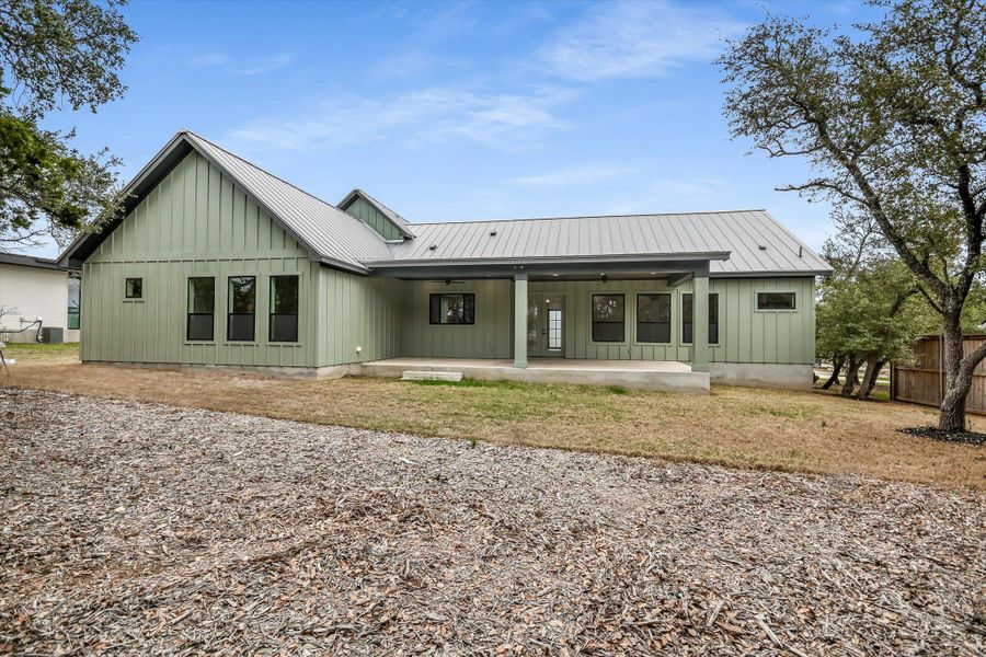 Back of property featuring board and batten siding, a patio area, and a metal roof