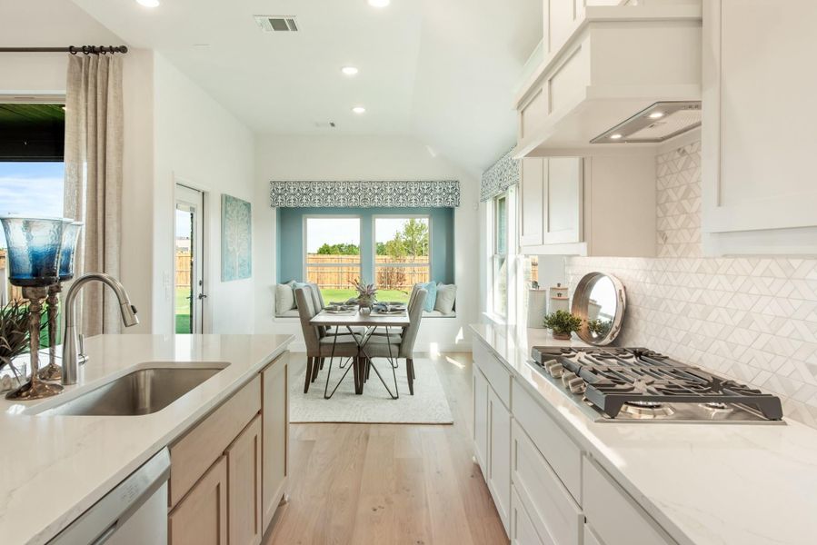 Kitchen with white cabinets, quartz countertops, gas cooktop, and tile backsplash, open to a dining nook with bay window seating. Kitchen with white cabinets, quartz countertops, gas cooktop, and tile backsplash, open to a dining nook with bay window seating.