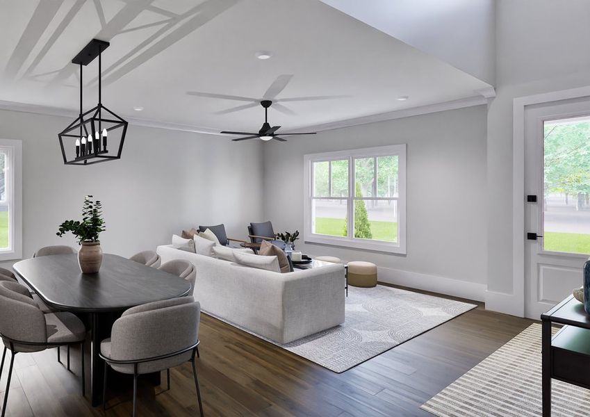 Modern open-concept family room with a large light gray sectional, accent chairs, ceiling fan, and view of kitchen and dining area.