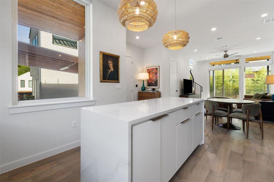 Kitchen featuring white cabinetry, modern cabinets, a kitchen island, decorative light fixtures, and light stone countertops
