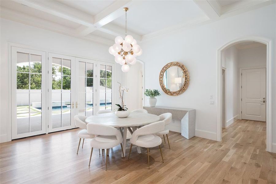 Dining area featuring a healthy amount of sunlight, coffered ceiling, and light wood flooring