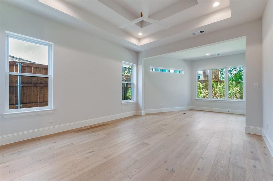 Spare room featuring light wood-style floors, a tray ceiling, ceiling fan, and recessed lighting Spare room featuring light wood-style floors, a tray ceiling, ceiling fan, and recessed lighting