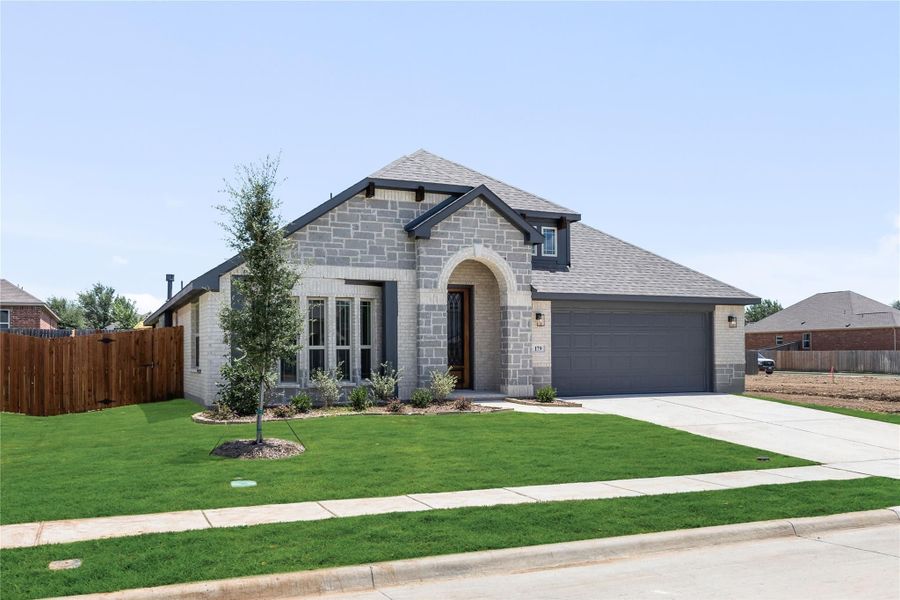 Single-story stone home with arched entry, two-car garage, and manicured front lawn Single-story stone home with arched entry, two-car garage, and manicured front lawn
