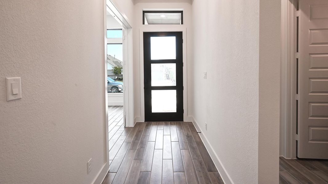 Entrance foyer featuring a textured wall and dark wood-type flooring