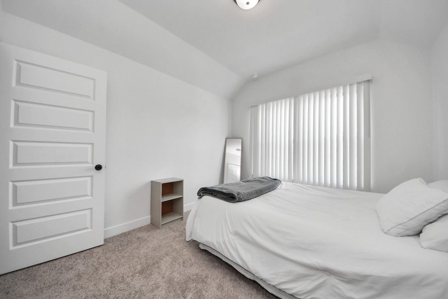 This is a bright, minimalistic bedroom featuring a small bed, neutral carpet, and a window with vertical blinds. There's a simple shelving unit and a wall mirror, creating a clean and serene atmosphere. This is a bright, minimalistic bedroom featuring a small bed, neutral carpet, and a window with vertical blinds. There's a simple shelving unit and a wall mirror, creating a clean and serene atmosphere.