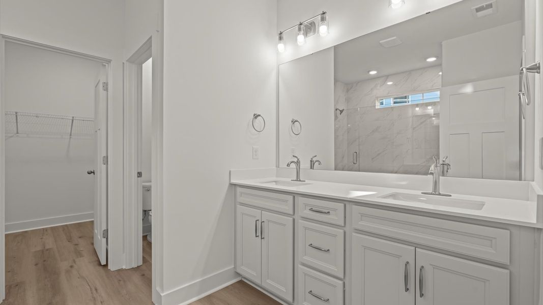 Highly functional and elegant en-suite with dual vanities, tiled walk-in shower, and refined finishes
