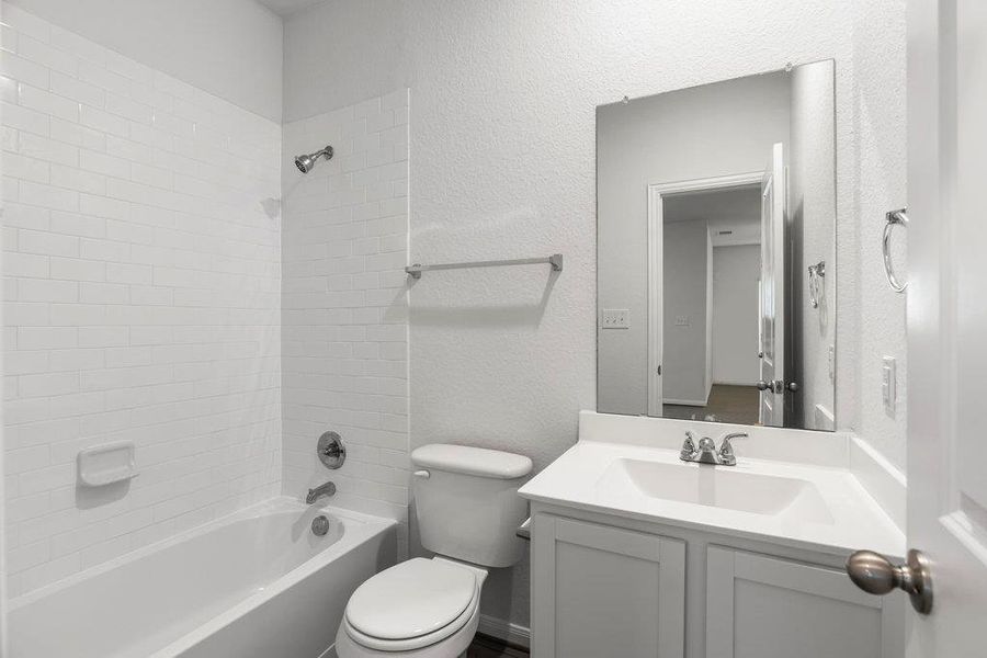 Full bathroom featuring a textured wall,  shower combination, and vanity