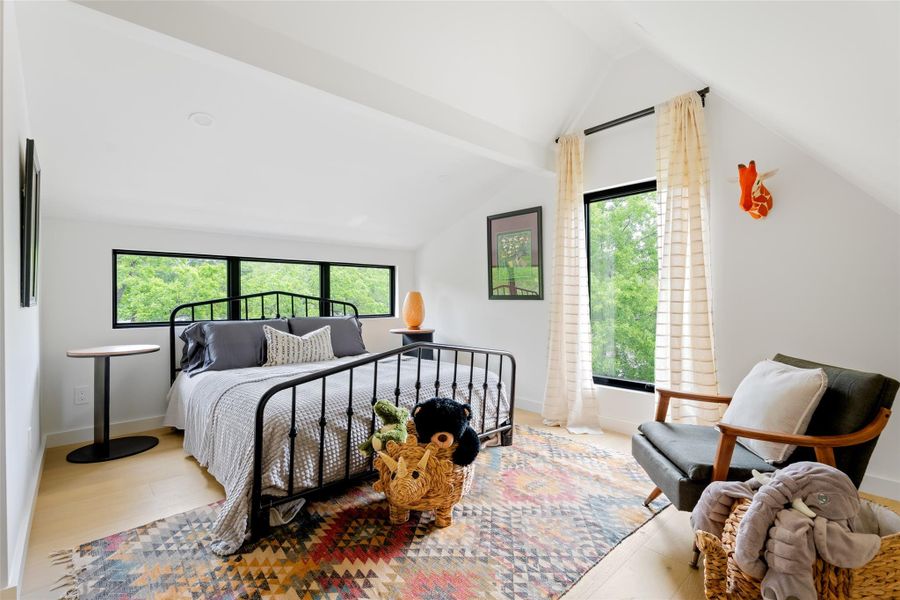 Bedroom with baseboards, lofted ceiling with beams, multiple windows, and wood finished floors