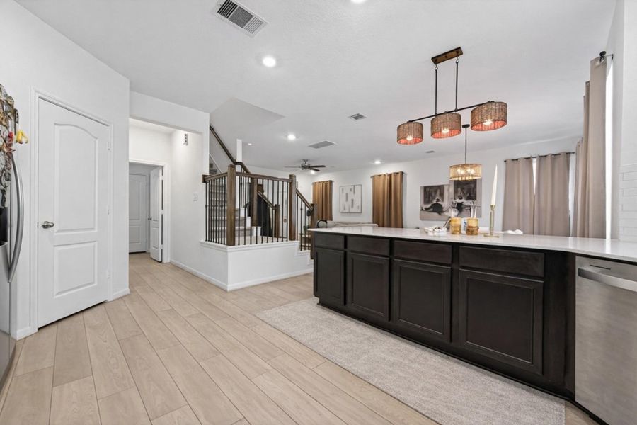 Sleek U-shaped kitchen with expansive quartz counters, dark cabinetry, and oversized island seating.